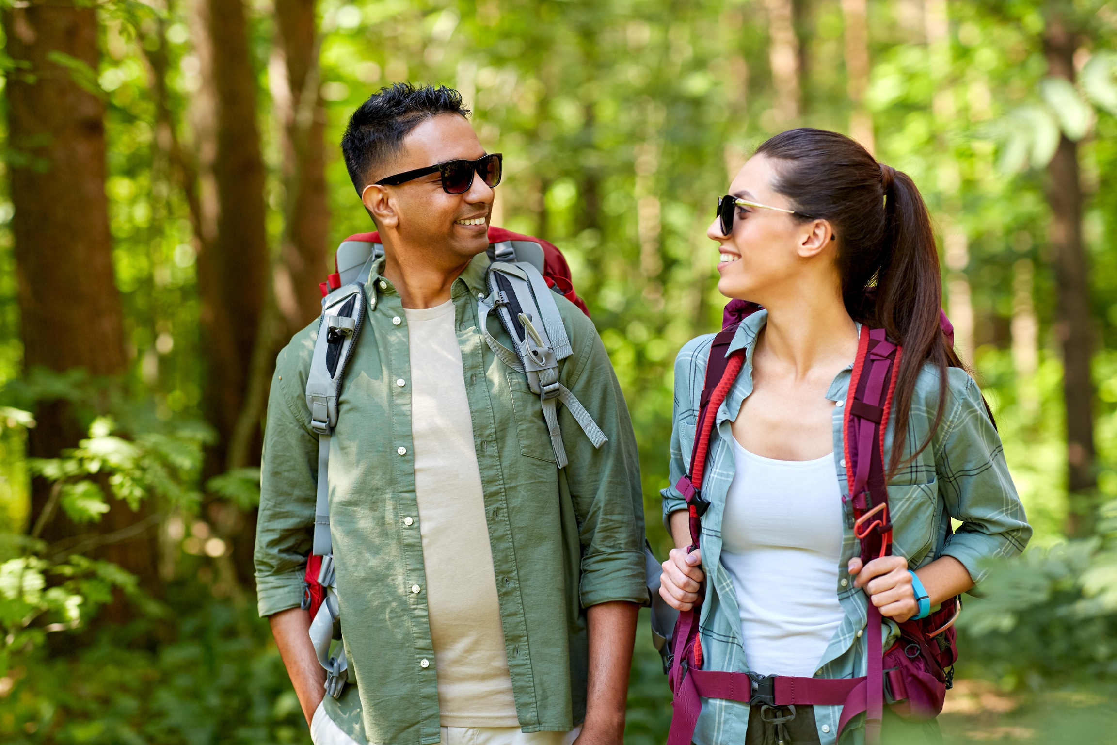 Mixed Race Couple with Backpacks Hiking in Forest